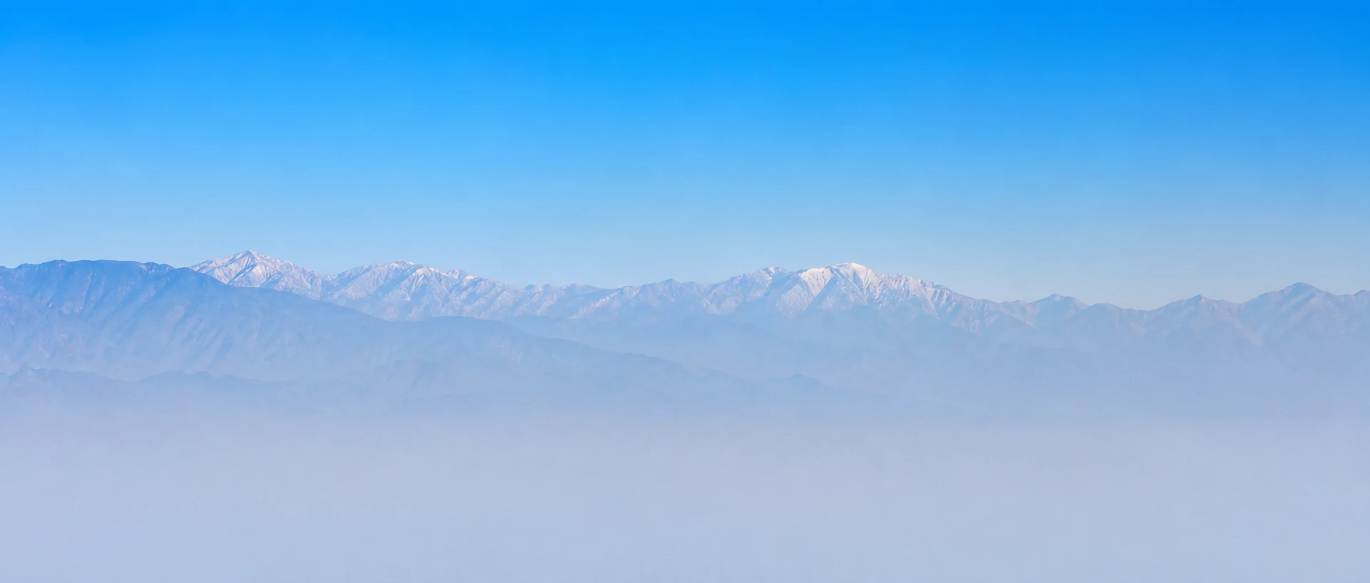 Mountain range behind a Los Angeles skyline and palm trees